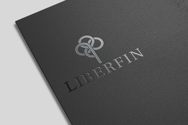 Na slici vidimo ugao crne poslovne mape položene na bijelu podlogu. Na mapi je crnim sjajnim tiskom otisnut logo tvtke Liberfin.