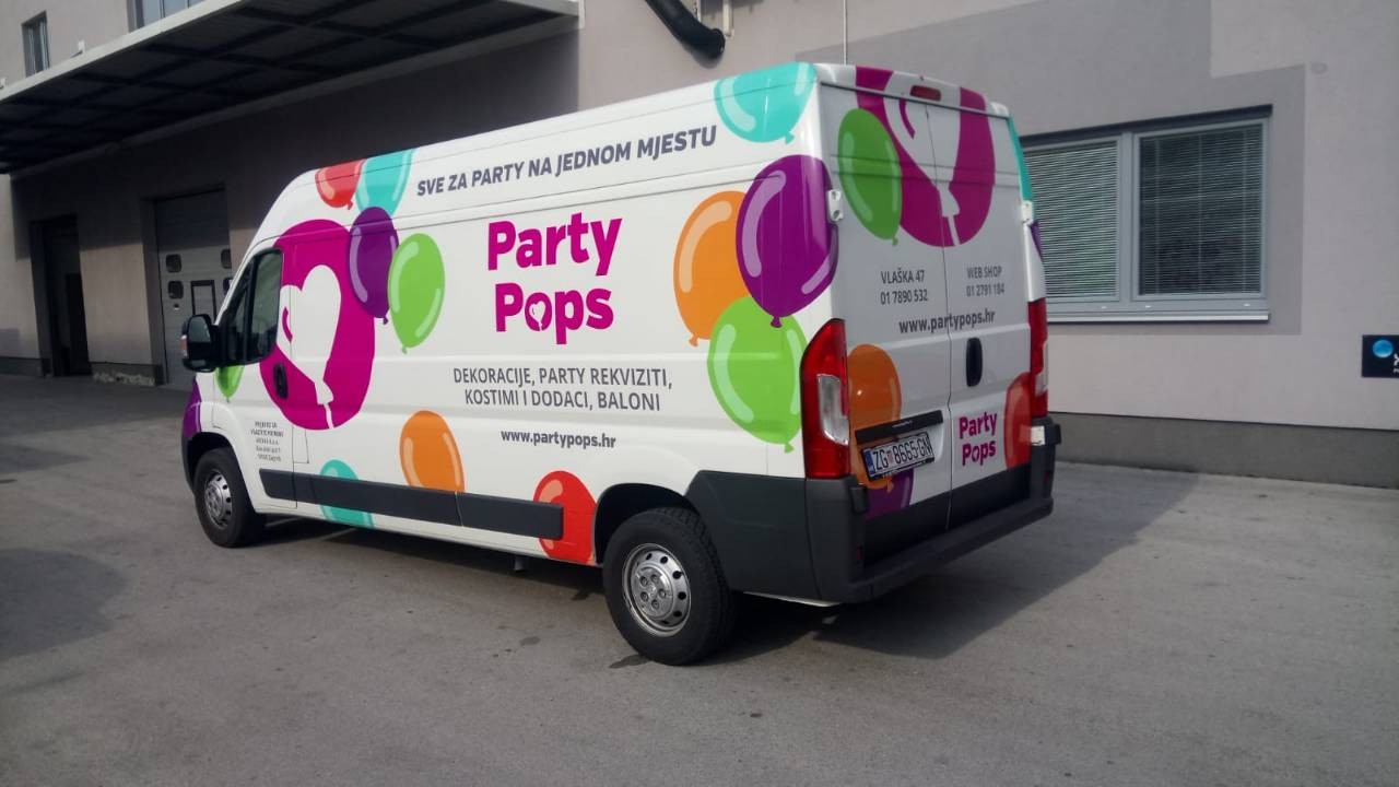 Oslikavanje vozila za tvrtku Party Pops iz Zagreba. Na slici je prikazan kombi šareno oslikan. U centru je logo tvrtke Party pops, krug magenta boje u kojemu je balon u obliku srca bijele boje. Logo je okružen drugim balonima u raznim bojama te se sa strane vidi natpis tekstualni Party Pops sa njihovim sloganom i osnovnim informacijama.
