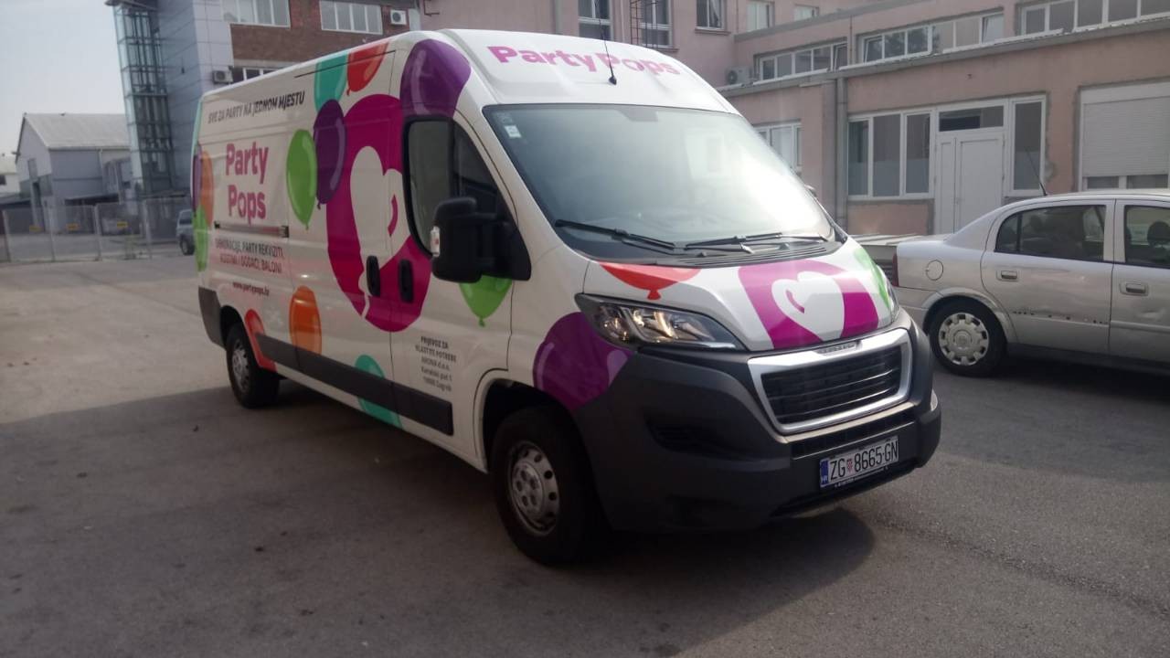 Oslikavanje vozila za tvrtku Party Pops iz Zagreba. Na slici je prikazan kombi šareno oslikan. U centru je logo tvrtke Party pops, krug magenta boje u kojemu je balon u obliku srca bijele boje. Logo je okružen drugim balonima u raznim bojama te se sa strane vidi natpis tekstualni Party Pops sa njihovim sloganom i osnovnim informacijama.