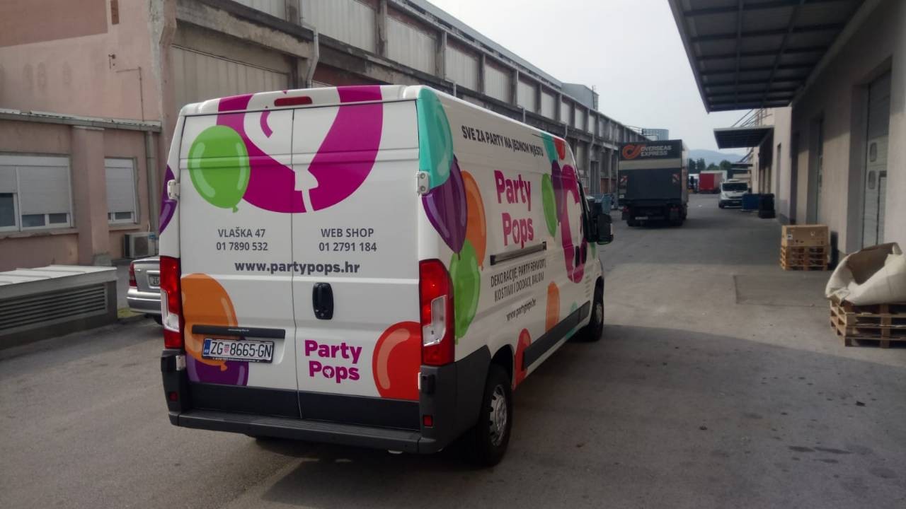 Oslikavanje vozila za tvrtku Party Pops iz Zagreba. Na slici je prikazan kombi šareno oslikan. U centru je logo tvrtke Party pops, krug magenta boje u kojemu je balon u obliku srca bijele boje. Logo je okružen drugim balonima u raznim bojama te se sa strane vidi natpis tekstualni Party Pops sa njihovim sloganom i osnovnim informacijama.