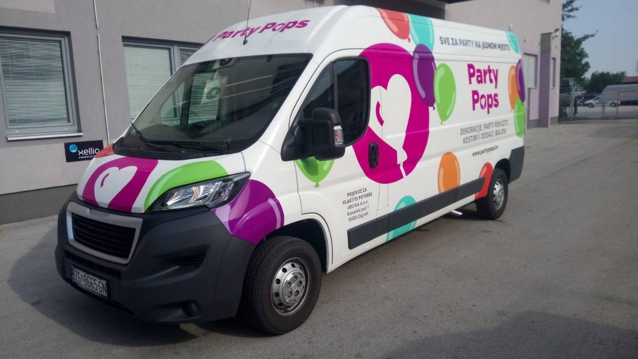 Oslikavanje vozila za tvrtku Party Pops iz Zagreba. Na slici je prikazan kombi šareno oslikan. U centru je logo tvrtke Party pops, krug magenta boje u kojemu je balon u obliku srca bijele boje. Logo je okružen drugim balonima u raznim bojama te se sa strane vidi natpis tekstualni Party Pops sa njihovim sloganom i osnovnim informacijama.