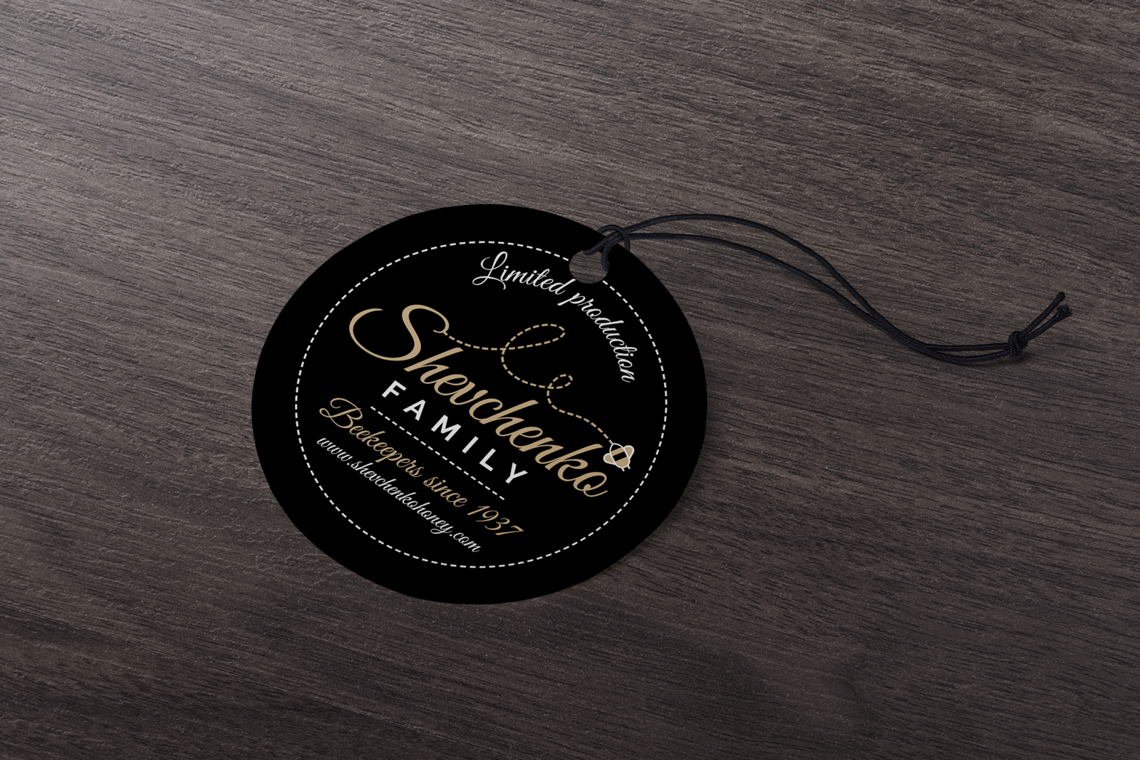 Dizajn privjesnice za med za tvrtku Shevchenko. Na slici se nalazi crna privjesnica za pakovanje meda. Crna privjesnica sa zlatnim i bijelim slovima i ikonama. Položena na drveni stol.